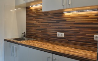 Holzrückwand und Glas statt Fliesen: Einbauküche mit integrierter Beleuchtung